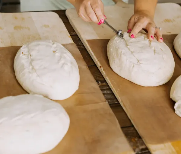 Hands scoring sourdough loaves during a Sugar Street baking class.